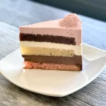Neapolitan cake slice with layers of strawberry, chocolate, and vanilla sponge and mousse, Trafiq Bakery Vancouver
