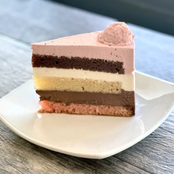 Neapolitan cake slice with layers of strawberry, chocolate, and vanilla sponge and mousse, Trafiq Bakery Vancouver