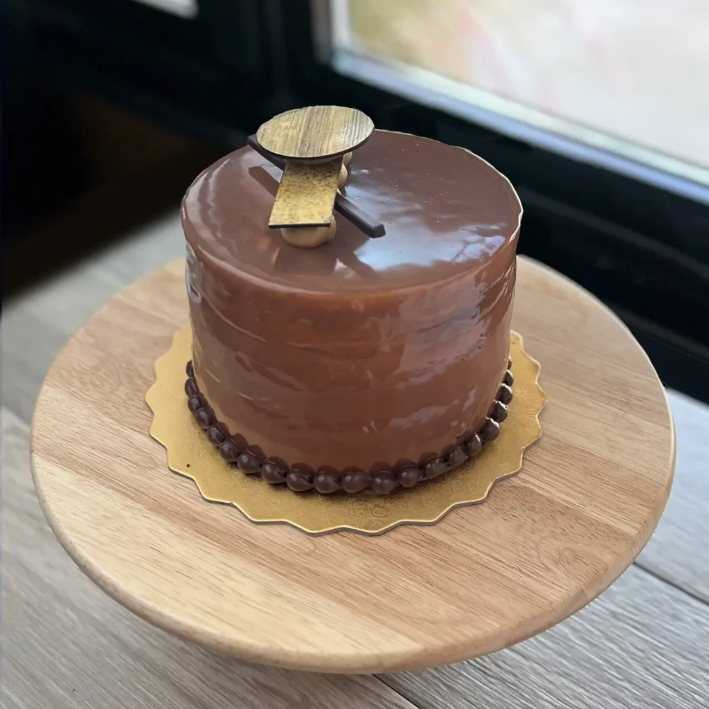 Chocolate Brulee Cake with glossy chocolate glaze, and decorated with gold details.