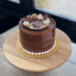 Pumpkin Spice Latte cake with chocolate mocha mousse, pumpkin pie layers, chocolate glaze, and piped whipped cream topped with namelaka