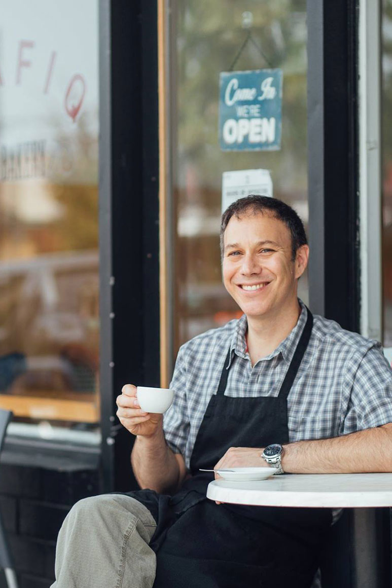 Owner of Trafiq Cafe & Bakery sitting outside of the cafe