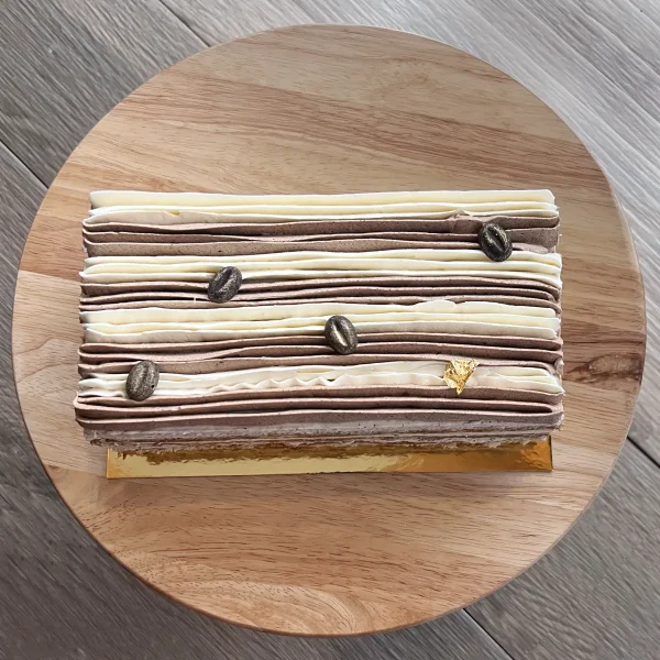 Top of coffee tres leches cake with striped icing and gold decoration