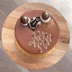 Top of festive Gingerbread cake with fancy white icing, chocolate bells and gingerbread man on chocolate glaze