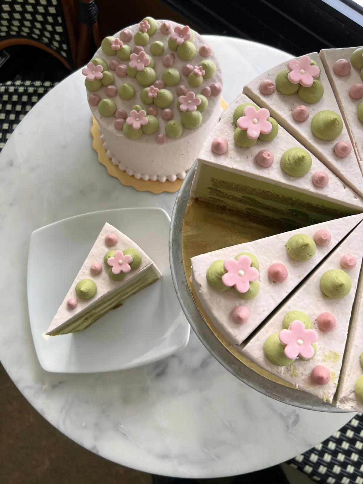 Top view of Sakura cake with pink icing and pink flowers on marble cafe table at Trafiq. 