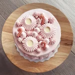 Top of pink holiday cake with pink icing rosettes and candy canes