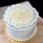 Close-up of passionfruit lime cake finished with whipped ganache topped with elegant textures.